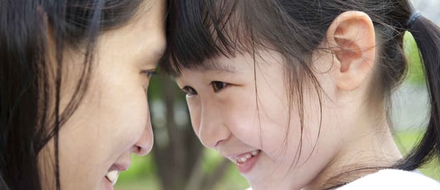 Mother and young daughter smiling at eachother